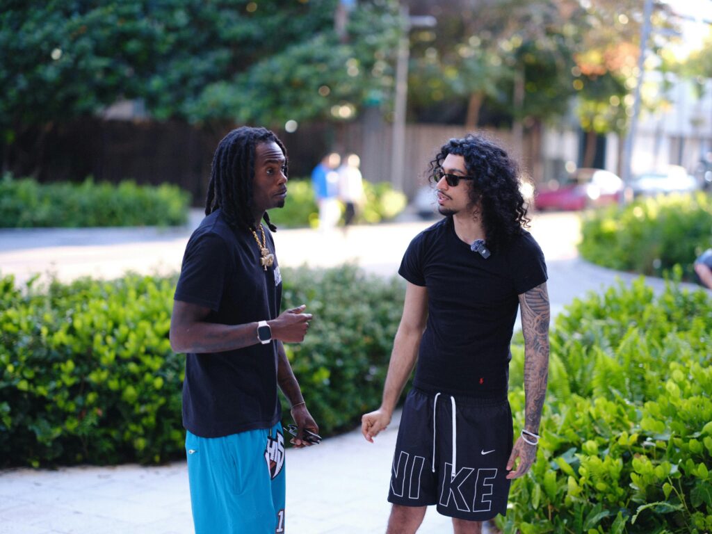 The Real Talk Two young men having a casual conversation on a sunny day outdoors.